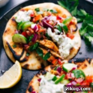 Two finished chicken shawarma wraps topped with delicious vegetables and sauce, ready to eat.