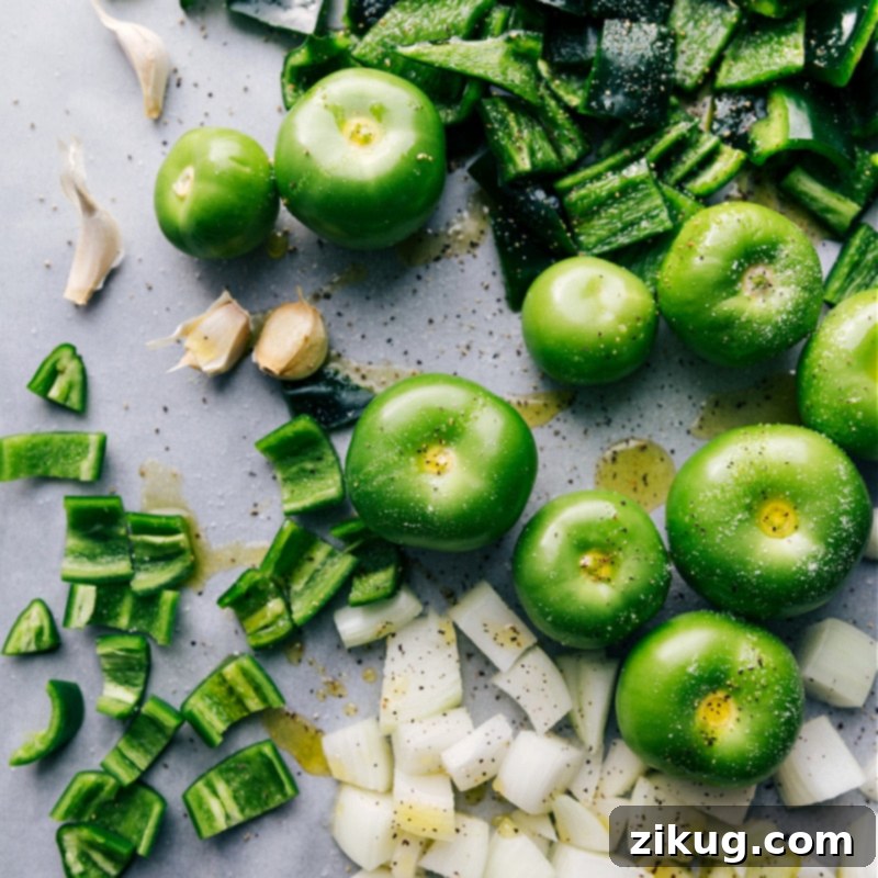 Fresh ingredients laid out: vibrant green tomatillos, poblano peppers, jalapeños, yellow onion, and garlic cloves, essential for making the green enchilada sauce.