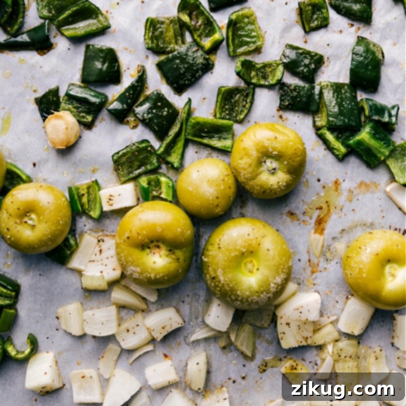 A sheet pan loaded with perfectly roasted tomatillos, poblano peppers, jalapeños, onions, and garlic cloves, fresh out of the oven, charred and caramelized for maximum flavor.