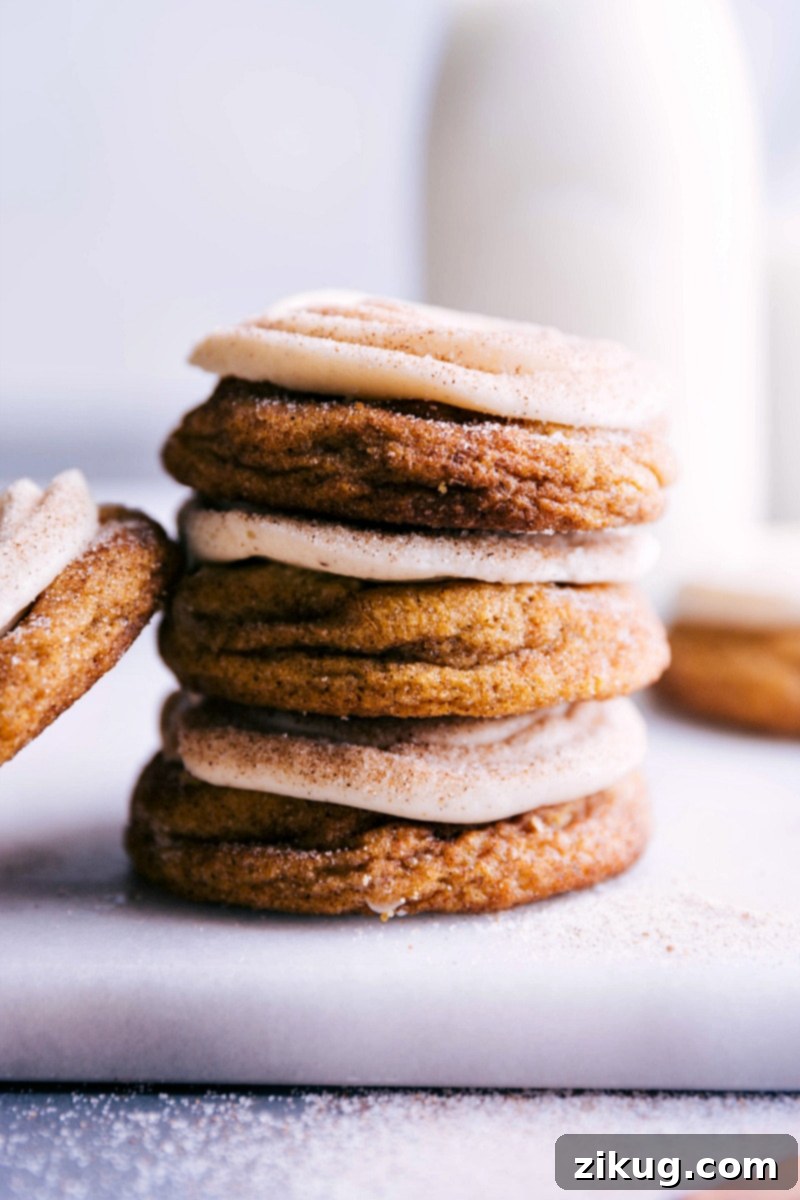 A beautifully arranged plate of finished Pumpkin Cinnamon Roll Cookies, each adorned with creamy frosting and a sprinkle of spice, showcasing their irresistible appeal and rich texture, promising a delightful culinary experience.