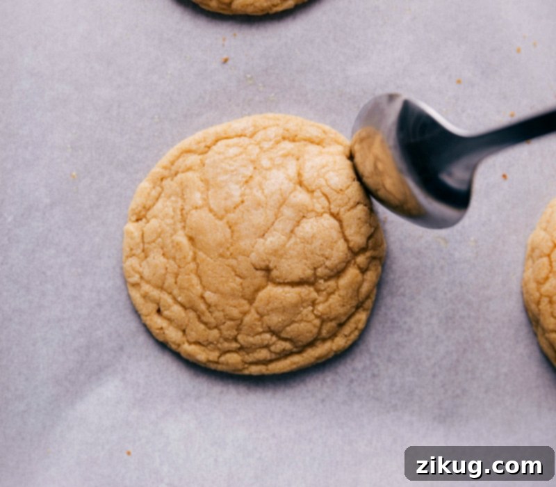 Using the back of a spoon to push in the edges of just-baked cookies, creating crispy edges while the cookies are still warm.