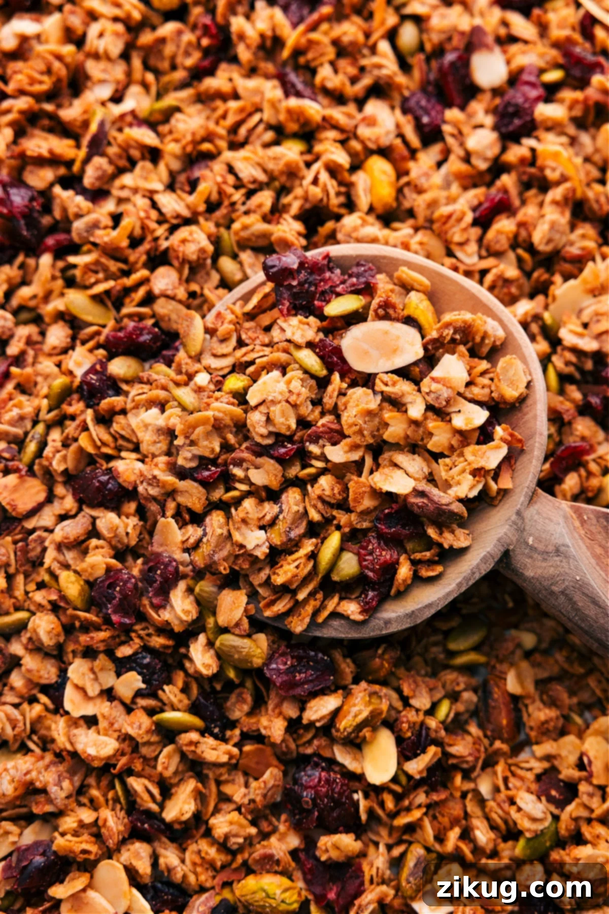 The Best Homemade Granola Recipe A big scoop of golden-brown granola on a parchment-lined baking sheet, ready to be enjoyed.