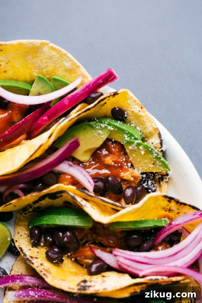 Chipotle chicken tacos artfully arranged on a platter, generously topped with an array of fresh vegetables, black beans, and a sprinkle of cheese.
