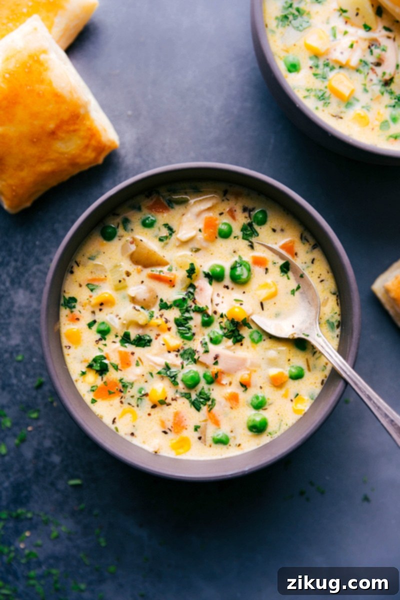 Hearty Chicken Pot Pie Soup - A Comforting Bowl of Warmth A steaming bowl of hearty Chicken Pot Pie Soup, filled with tender chicken, carrots, peas, and potatoes, garnished with fresh herbs, and accompanied by golden, flaky puff pastry squares.