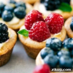 Mini fruit tarts topped with raspberries, blueberries, blackberries, and fresh mint.