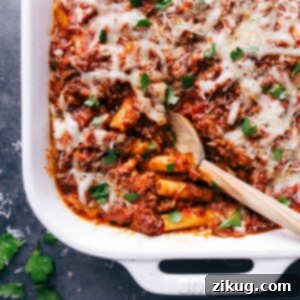 Finished baked ziti in a casserole dish, with a scoop taken out to reveal the warm, flavor-packed layers inside.