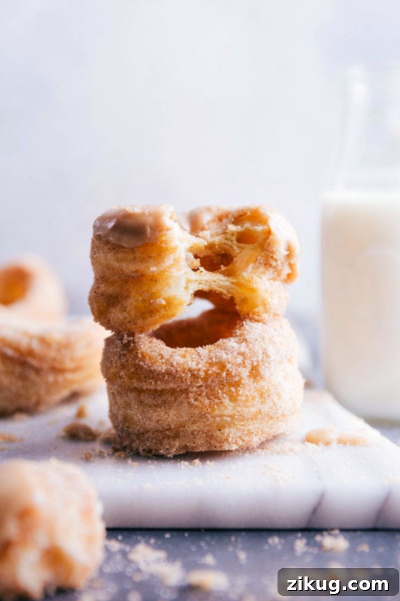 Two cronuts, one bitten to reveal the fluffy, layered interior.