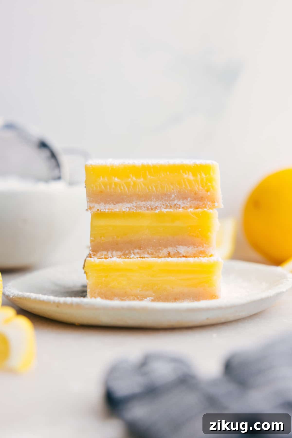 Stacked lemon bars dusted with powdered sugar, showcasing their vibrant yellow filling and golden crust.