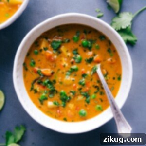 A close-up shot of the finished Chicken Curry Soup, steaming hot and ready to be served, garnished with fresh herbs.