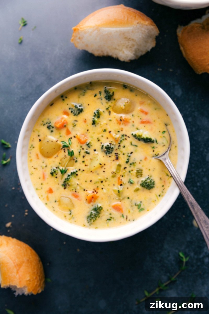 This creamy, hearty Broccoli Potato Cheese Soup is loaded with crisp-tender broccoli, golden buttery potatoes, and even more veggies. On a cold, drizzly day, there's nothing like enjoying this soup served in a crusty sourdough bread bowl or with dinner rolls for dipping! Big bowl of creamy Potato Broccoli Cheese Soup, garnished with fresh chives, ready to be enjoyed.