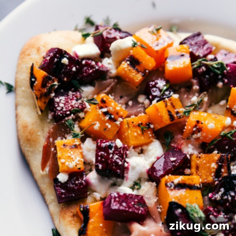 Close-up overhead image of a section of the grilled beet and goat cheese flatbread, highlighting the textures and colors of the toppings.