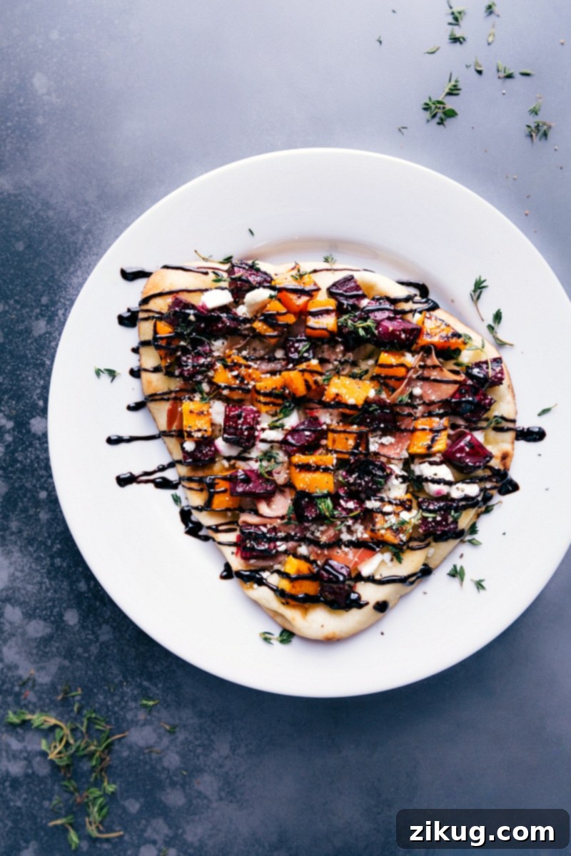 Overhead image of the finished beet and goat cheese flatbread, generously drizzled with balsamic glaze, beautifully arranged and ready for serving.