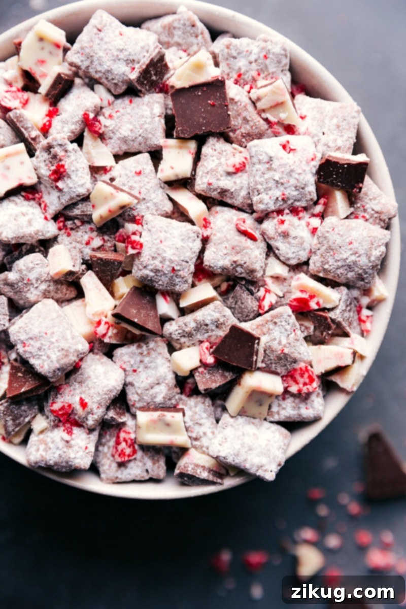 Festive Peppermint Bark Muddy Buddies Ready to Enjoy A bowl of Chex mix muddy buddies peppermint bark, a delicious and festive snack, coated in powdered sugar and crushed peppermint, ready to be enjoyed.