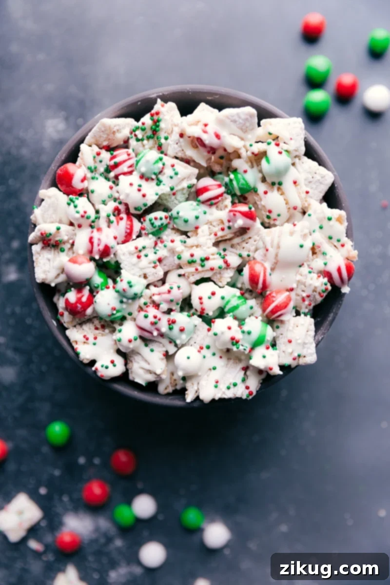 Overhead view of a vibrant Sugar Cookie Snack Mix, featuring crunchy cereal, festive M&Ms, and a delicate white chocolate drizzle with colorful sprinkles.