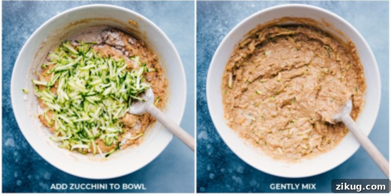 Process shot showing grated zucchini being folded into the prepared bread batter in a mixing bowl.