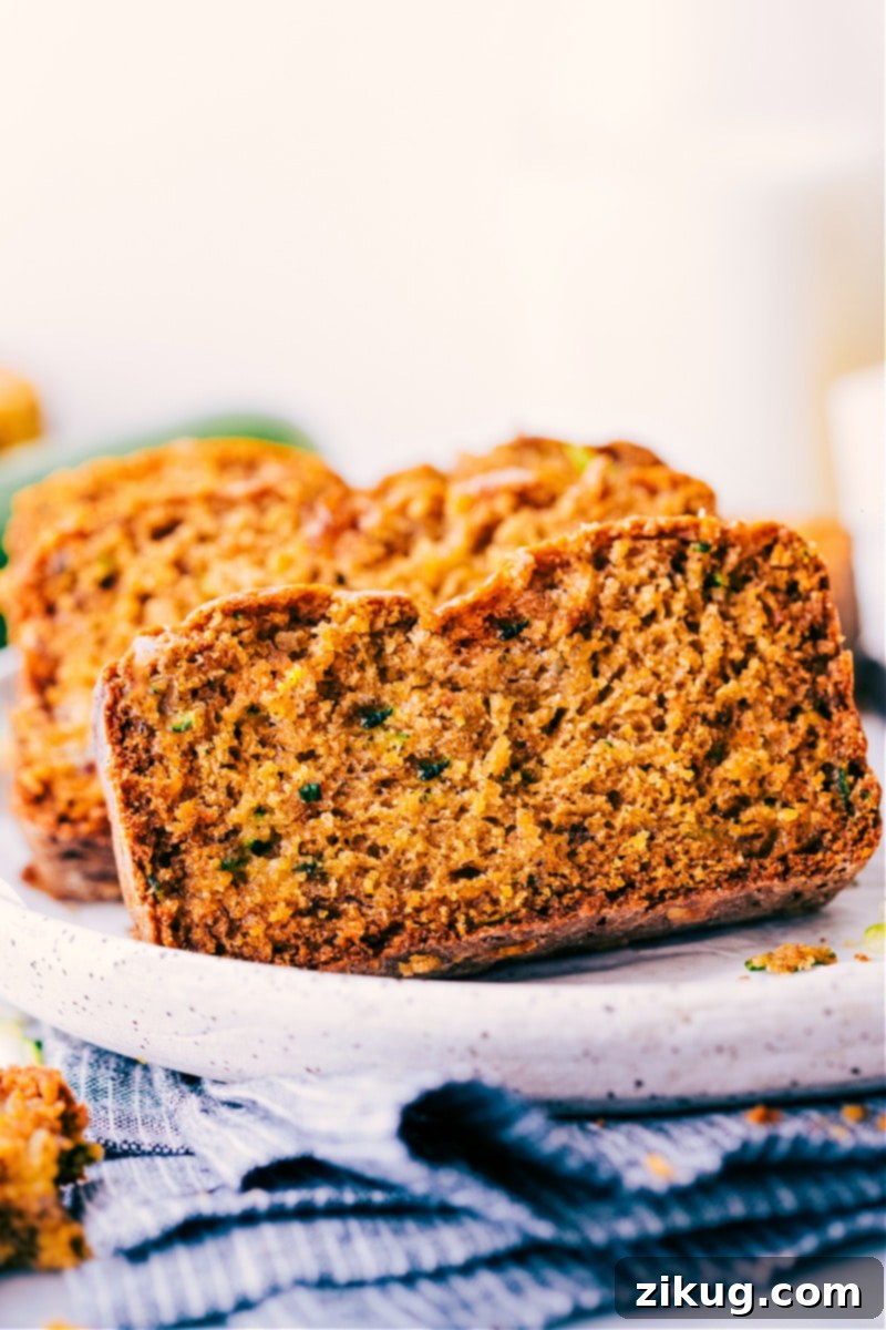 Close-up image of perfectly sliced Healthy Zucchini Bread, revealing its moist crumb and scattered flecks of zucchini.