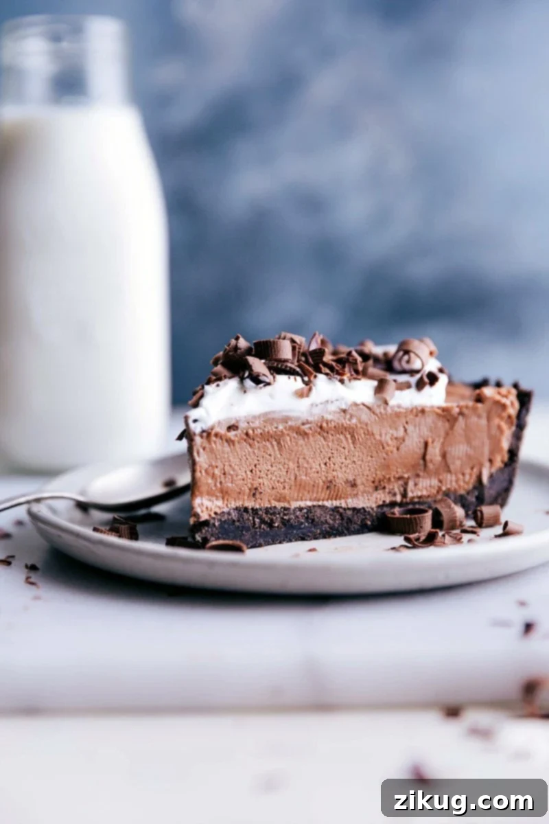 A decadent slice of Nutella pie, crowned with whipped cream and chocolate shavings, on a plate with a spoon, inviting a bite.