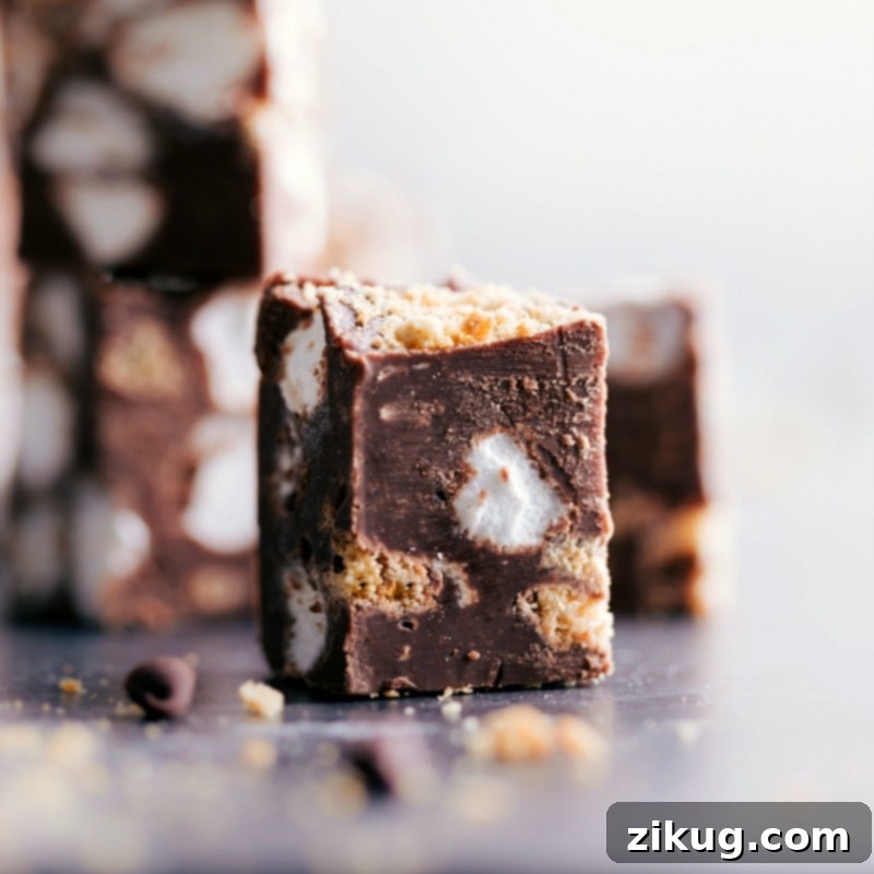 Delicious close-up of Easy Stovetop S'mores Fudge: Indulge in rich chocolate, crunchy graham crackers, and gooey marshmallows. #fudge #smoresfudge #dessert #chocolate #marshmallows #easyrecipe A close-up view of a single piece of S'mores Fudge, highlighting its rich texture, visible graham cracker pieces, and soft marshmallow bits.
