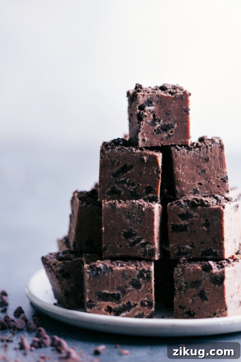 Decadent Oreo Chocolate Fudge 2 A stack of perfectly cut Chocolate-Covered Oreos Fudge pieces on a plate, showcasing the chocolate and Oreo layers.