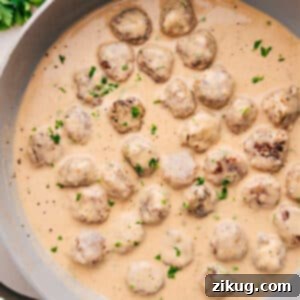 A plate of Swedish Meatballs with gravy, mashed potatoes, and lingonberry jam.