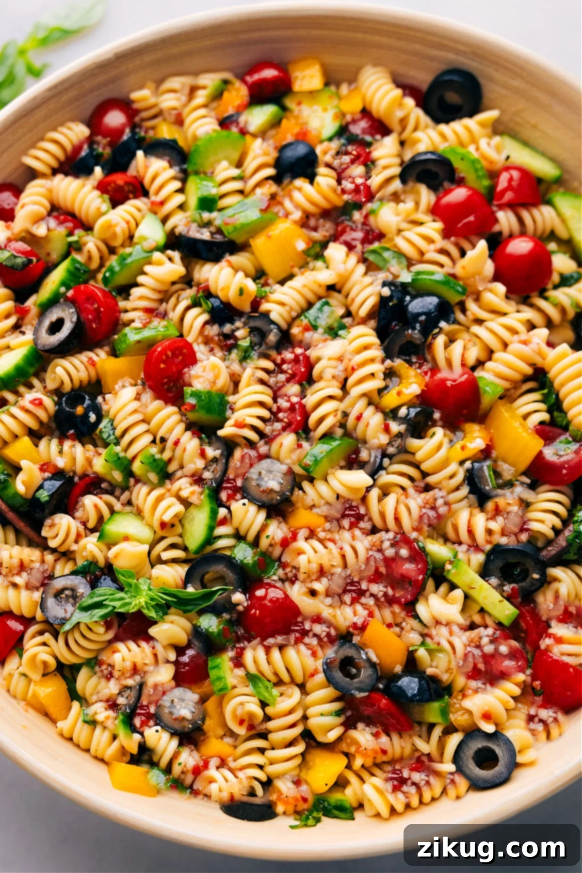 The Best Easy Pasta Salad Recipe A vibrant bowl of freshly made pasta salad, bursting with colorful vegetables and tender spiral pasta, ready to be served and enjoyed. The light catches the glistening dressing, highlighting the freshness of the ingredients.