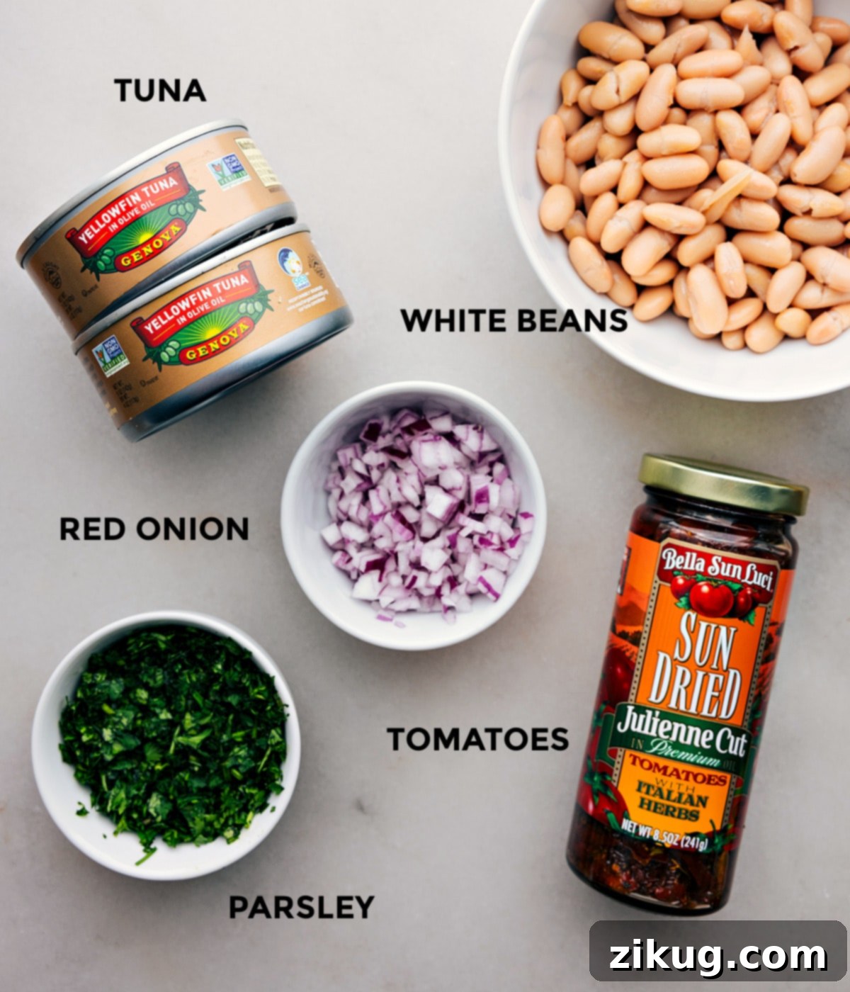 Mediterranean Tuna & White Bean Bowl 3 All the vibrant ingredients for Tuna and White Bean Salad, including flaky tuna, hearty white beans, thinly sliced red onion, juicy sun-dried tomatoes, and fresh parsley, meticulously prepped and arranged for effortless assembly.