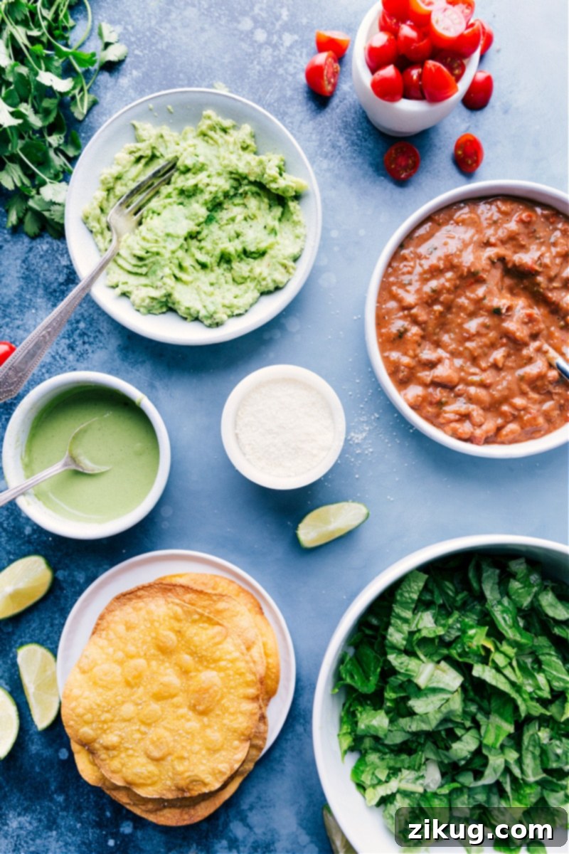Key Ingredients for Crispy Bean Tostadas: Avocados, Pinto Beans, Corn Tortillas, Fresh Vegetables, and a Zesty Cilantro-Lime Sauce. A vibrant flat lay image showcasing all the fresh ingredients for making Bean Tostadas: ripe avocados, cilantro, limes, pinto beans, corn tortillas, cherry tomatoes, romaine lettuce, and cotija cheese.