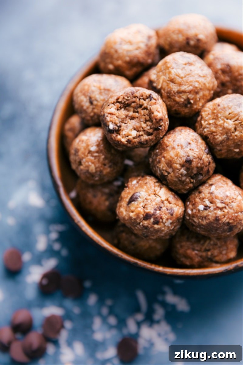 A close-up shot of a bowl of Oatmeal Energy Bites, with one bite taken out of a ball, revealing the moist, chewy interior.
