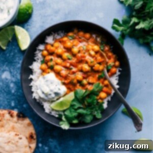 Delicious Chickpea Curry in a bowl with basmati rice, warm naan, and fresh cilantro garnish, showcasing its rich, creamy texture.