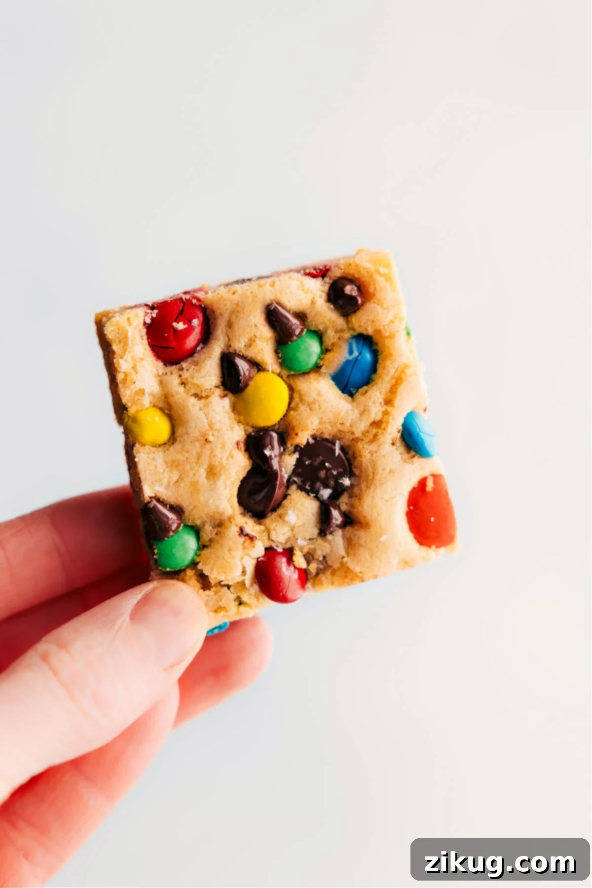 M&M Cookie Bars being held up, showcasing their colorful appeal and delicious texture.