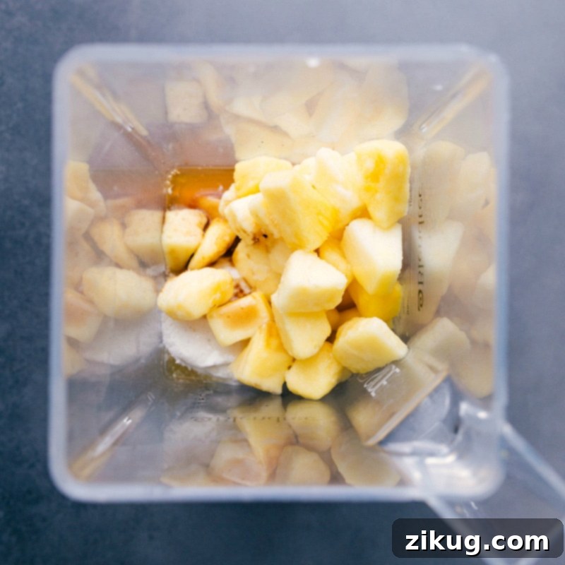 Blender full of frozen pineapple and other ingredients.