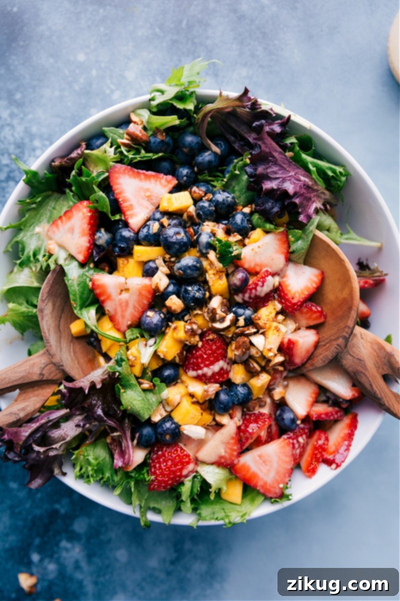 Experience the ultimate fresh Mango Salad, loaded with sweet mango, juicy berries, and crunchy cinnamon almonds, all brought together by a unique cinnamon-yogurt dressing. A truly vibrant and healthy fruit salad recipe you'll crave! Overhead view of a beautiful Mango Salad with blueberries and strawberries, ready to be served.
