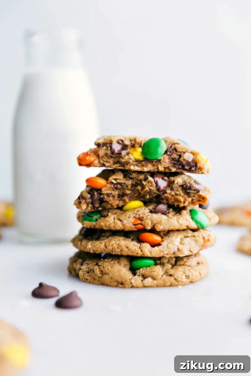 Healthy Gluten-Free Monster Cookies Healthy Monster Cookies stacked on top of each other with one broken in half showing off the middle, showcasing their soft, chewy texture and delicious mix-ins.