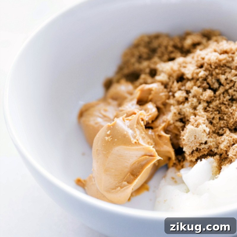 Epic Gluten-Free Monster Cookies 3 Peanut butter, coconut oil, and sugar in a bowl, ready to be mixed for the gluten-free monster cookie dough, highlighting the simple starting ingredients.