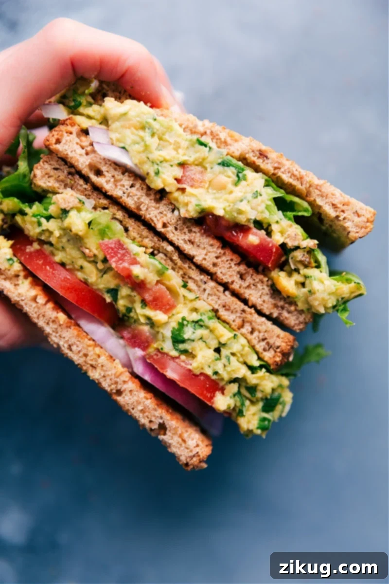 This Chickpea Salad Sandwich is loaded with a creamy chickpea filling that includes lots of fresh veggies and herbs. Pile it on some toasted bread with lettuce, tomato, and onion for a hearty, flavorful, and nutritious meal. Recipe via chelseasmessyapron #dinner #lunch #vegan #vegetarian #healthy #quick #easy #simple #best #tomatoes #chickpea #salad #sandwich Delicious Chickpea Salad Sandwich on toasted bread with lettuce, tomato, and onion