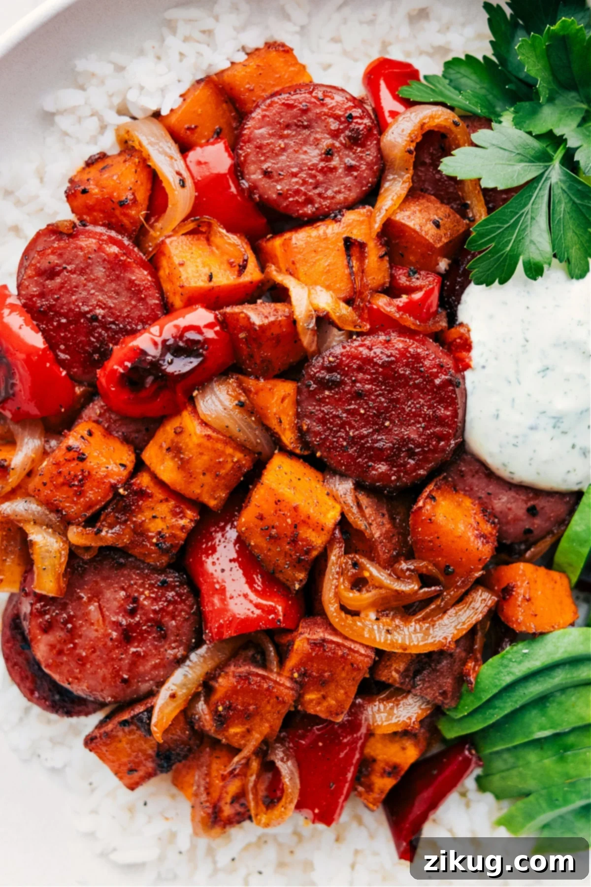 Sweet Potato and Sausage Over Rice - Ready to Serve Hearty dish of sweet potato and sausage served over a fluffy bed of rice on a plate, generously topped with a homemade sauce and ready to be enjoyed.