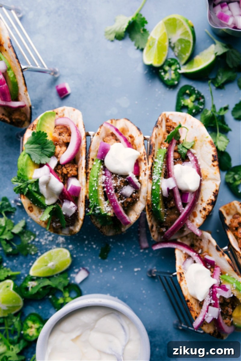 Flavorful Ground Pork Tacos with fresh toppings and a creamy lime drizzle. A quick and easy dinner solution. Three perfectly assembled ground pork tacos with lime crema, avocado, and cilantro