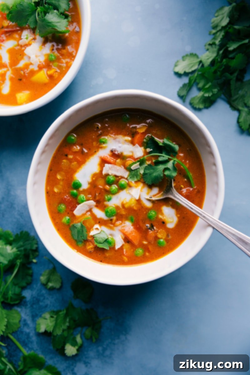 This vibrant Curry Lentil Soup combines an array of veggies, red lentils, a robust seasoning blend, and creamy coconut milk to deliver an unforgettable warming meal. This healthy, quick, easy, simple, protein-rich, whole30, vegan, vegetarian dinner recipe is packed with peas, curry, and lentils for a truly satisfying soup experience. Two bowls of vibrant Curry Lentil Soup, garnished with fresh herbs and a swirl of coconut milk, ready to be enjoyed.