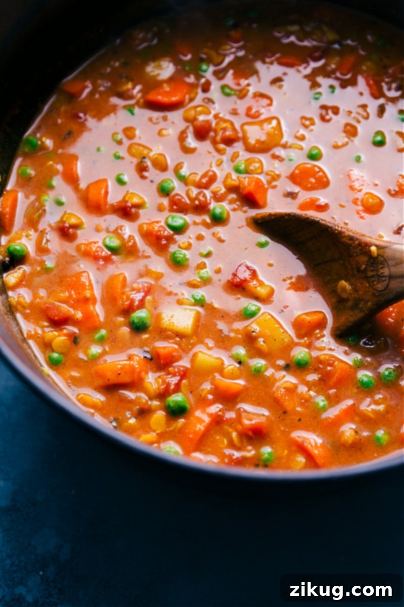 Curry Lentil Soup combines an array of veggies, red lentils, a robust seasoning blend, and creamy coconut milk to deliver an unforgettable warming meal. This healthy, quick, easy, simple, protein-rich, whole30, vegan, vegetarian dinner recipe is packed with peas, curry, and lentils for a truly satisfying soup experience. A close-up, enticing view of a bowl of Curry Lentil Soup, garnished and ready to eat, highlighting its rich texture and vibrant colors.