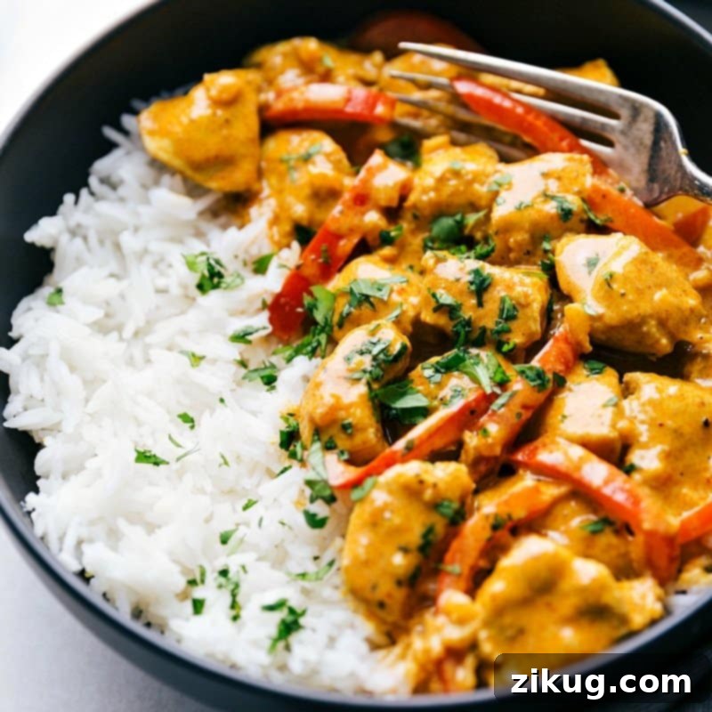 The finished chicken coconut curry on top of rice, garnished with fresh herbs, warm and ready to be enjoyed.