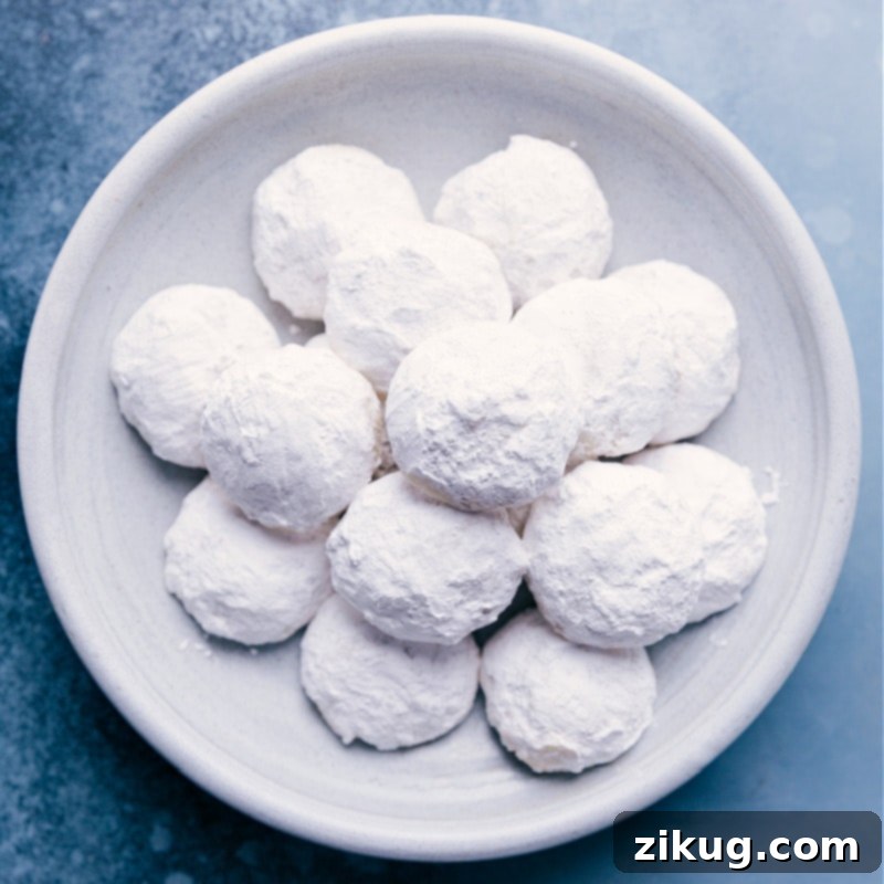 A plate of perfectly round Mexican Wedding Cookies, coated in powdered sugar.