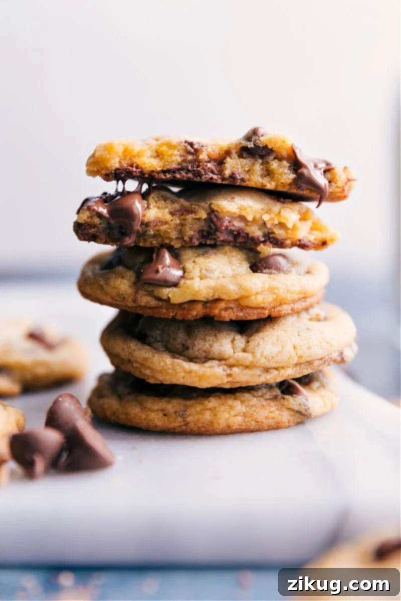 Stack of warm, soft Chocolate Chip Pudding Cookies, with one broken in half to reveal the gooey chocolate center and tender crumb.