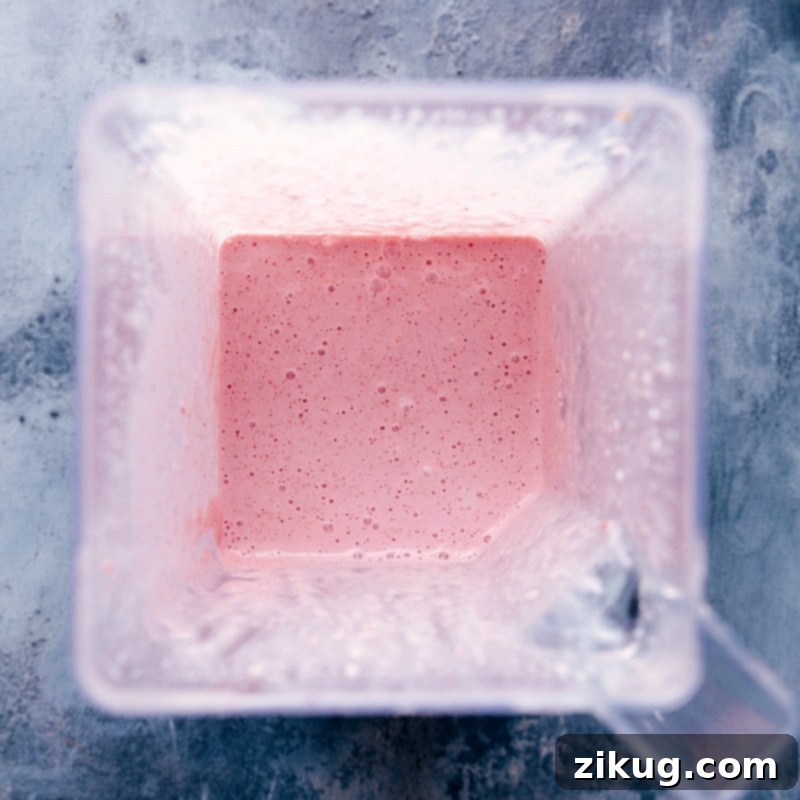 Freshly blended strawberry milkshake in the blender jar, ready to be poured.