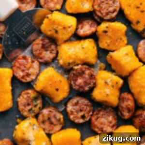 Final plated dish of roasted sweet potato gnocchi and sausage with pesto, garnished with fresh basil.