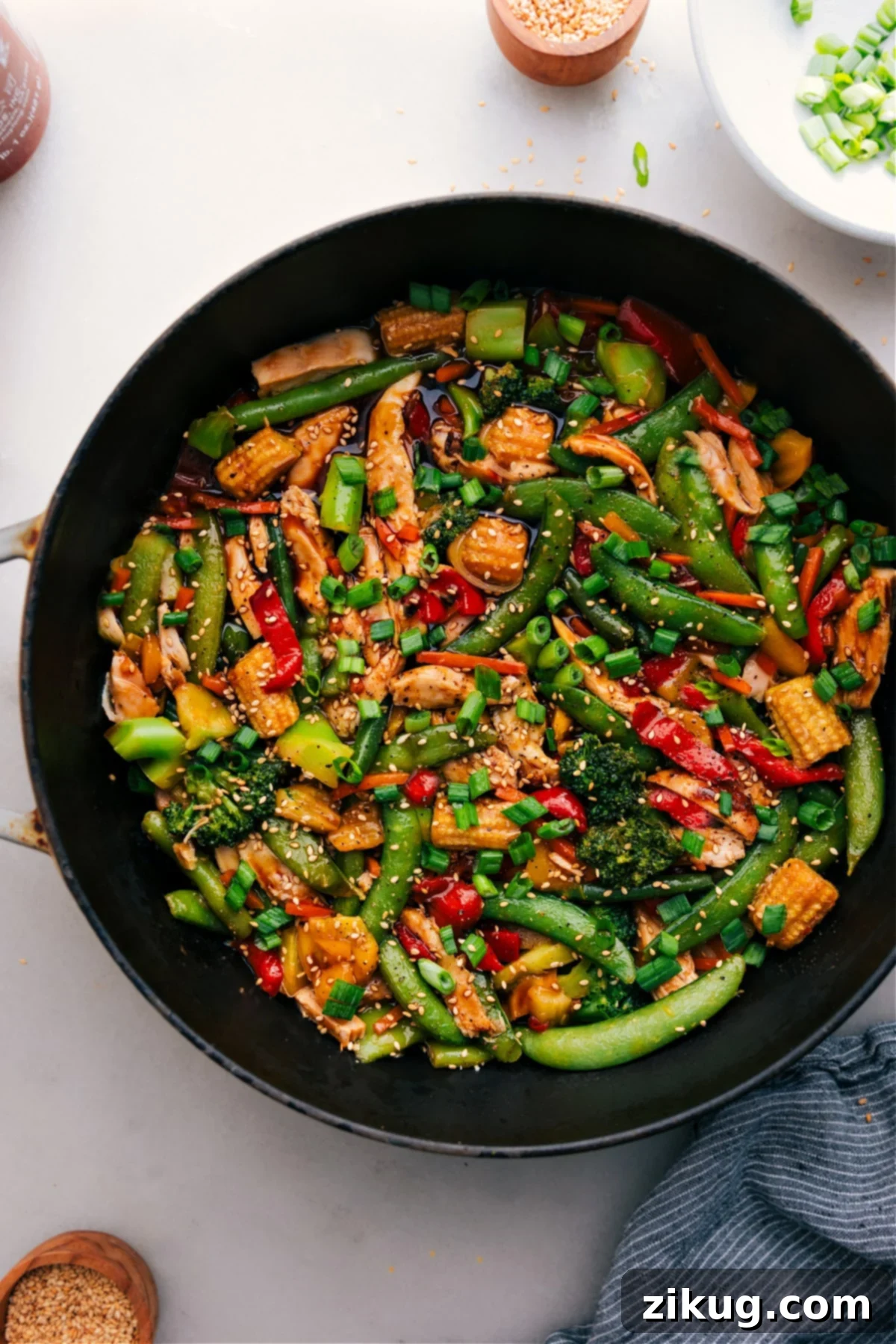 Simple And Delicious Rotisserie Chicken Stir-Fry Delicious Rotisserie Chicken Stir-Fry served in a skillet, garnished with fresh green onions and sesame seeds, ready to eat.