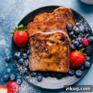 A stack of perfectly cooked cinnamon-sugar French Toast, drizzled with caramel syrup and topped with whipped cream and fresh berries. The dish is presented on a white plate, ready to be enjoyed.