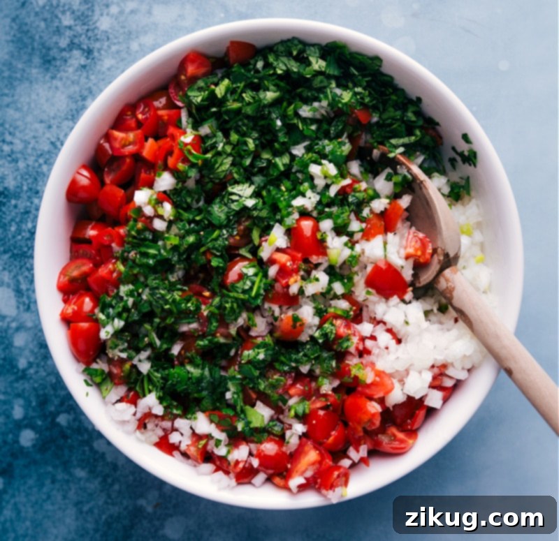 Freshly tossed Pico de Gallo, also known as Salsa Fresca, ready to be served as a healthy and flavorful side dish or topping. Overhead image of Pico de Gallo being tossed gently in a bowl