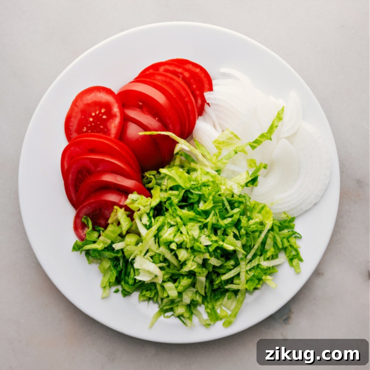 How To Make Italian Hoagies Freshly chopped tomatoes, thinly sliced white onions, and finely shredded iceberg lettuce are neatly arranged, showcasing their vibrant colors and readiness for the Italian Hoagies.