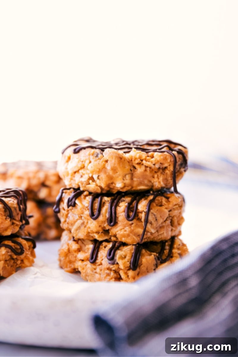 Indulge in these easy, quick, and healthy No-Bake Breakfast Cookies, featuring simple ingredients and a delightful chocolate finish. Ideal for any time of day! Close-up of three perfectly formed No-Bake Healthy Breakfast Cookies with a delicate chocolate drizzle.