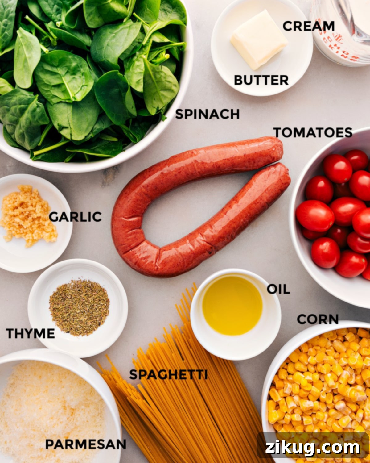Creamy Sausage and Sweet Corn Pasta 3 All ingredients laid out on a table, including prepped vegetables, smoked sausage, dry spaghetti, seasonings, olive oil, and parmesan cheese.